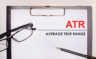 On a light wooden background glasses, a pen and a sheet of paper with the text ATR Average True...