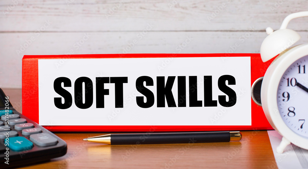 Poster red folder for papers with the text soft skills, white alarm clock, calculator and pen on the deskto