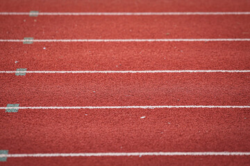 Fototapeta premium Running racetrack standard rubber surface with white lane outline. Sport and background photo. Selective focus.