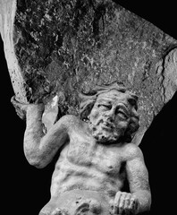 Very ancient stone statue of Sisyphus with stone. God Zeus punished Sisyphus: he had to roll very...