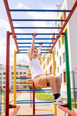Obraz premium A teenage boy is engaged on horizontal bars near the school