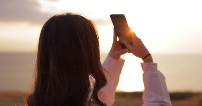 Woman take a photo of beautiful sea sunset