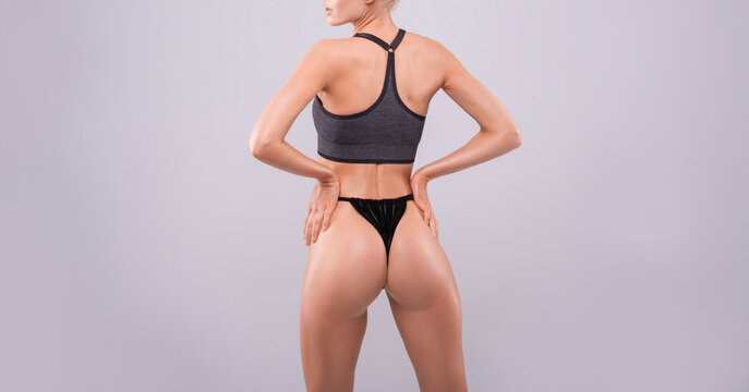 Image of a sports girl with pumped buttocks in a white studio. Fitness and bodybuilding concept.