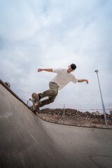 young male skater skates over the edge of a bowl at a skate park. vertical composition