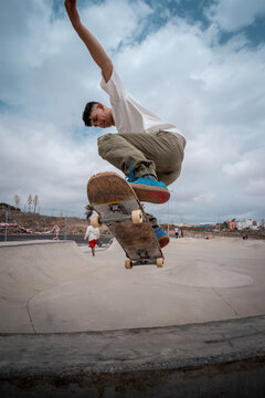 young skateboarder makes a trick called "Fakie noseblunt" in a skate park. vertical composition