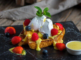 french toast with strawberry, blackberry, cream and basil served in a dish isolated on cutting board side view of breakfast on wooden background