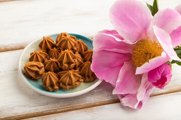 Homemade soft caramel fudge candies on white wooden, side view