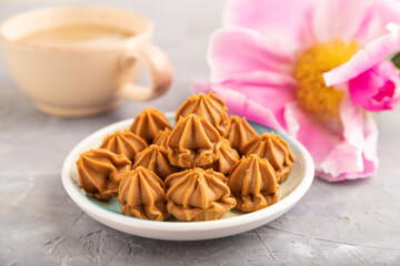 Homemade soft caramel fudge candies on gray concrete, side view, selective focus