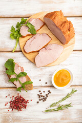 Smoked pork ham on cutting board on white wooden background. Top view, close up.