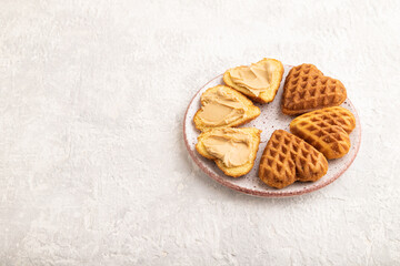 Homemade waffle with peanut butter on a gray concrete. side view, copy space.