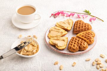 Homemade waffle with peanut butter on a gray concrete. side view, close up.