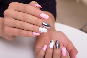 Fototapeta premium Beautiful female hands with colourful manicure nails, pink and silver colored gel polish