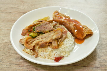 spicy stir fried barbecue pork neck with chili and basil leaf topping egg dressing sauce and rice on plate  