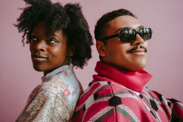 Thoughtful hipster woman with gay man against pink wall at home