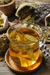 Freshly brewed tea and dried herbs on wooden table