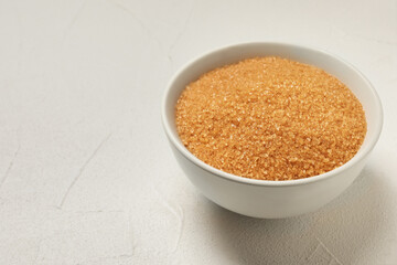 Brown sugar in bowl on white table. Space for text