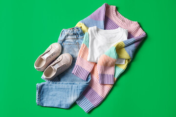 Stylish child clothes and shoes on green background, flat lay