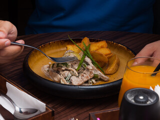 a man eats rustic potatoes with pork in cream sauce in a cafe. close-up