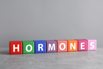 Word HORMONES made with colorful cubes on grey table