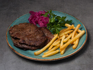 beef chop with french fries, garnished with red onion and herbs