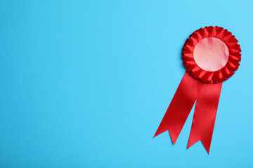 Red award ribbon on turquoise background, top view. Space for text