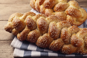 Homemade braided breads with sesame seeds on wooden table, closeup. Challah for Shabbat