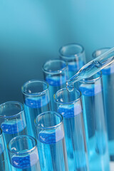 Dripping reagent into test tube on light blue background, closeup. Laboratory analysis