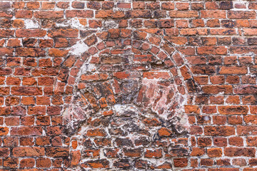 Alte beschädigte Wand oder Mauer aus rotem Backstein oder Ziegeln mit gemauertem Bogen
