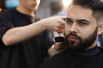 Professional hairdresser working with client in barbershop