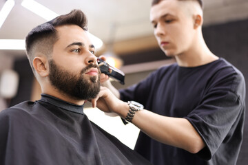 Professional hairdresser working with client in barbershop