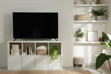 Fototapeta na wymiar Stylish wide TV set on stand in room