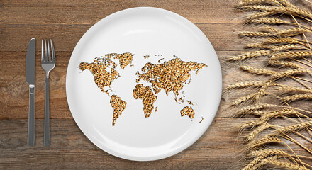 Global food crisis concept. World map made of wheat grains in plate, cutlery and spikes on wooden table, flat lay