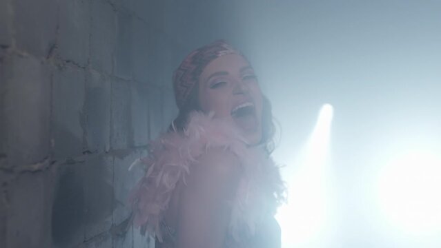 young beautiful girl sings near the stone wall. caucasian woman shoots a music video with dynamic light. a lady in a bandana moves beautifully to the music.