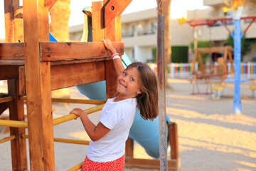 The girl rides on a swing in the playground. Children's outdoor carousels