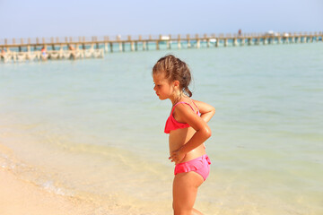 The child is resting in the summer on the sea. A tanned girl goes to the sea. Summer holiday with a child on the sea