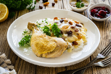 Boiled chicken thigh with white rice and lemon creamy sauce with raisins on wooden table