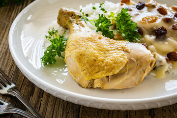 Boiled chicken thigh with white rice and lemon creamy sauce with raisins on wooden table