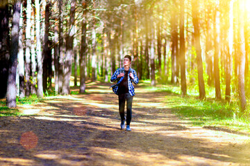 Fototapeta premium Teenage boy taking a walk in a sunlit summer park.