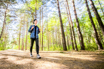 Fototapeta premium A young man is taking his journey through a green forest.