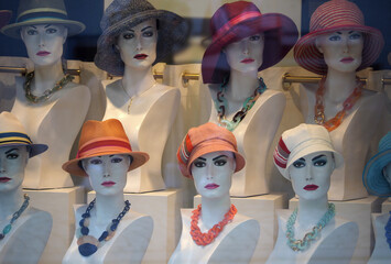 Mannequins in hats in a shop window - 517496214