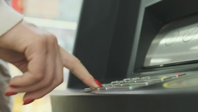 A young woman iusing an ATM machine to get money from her credit card.
