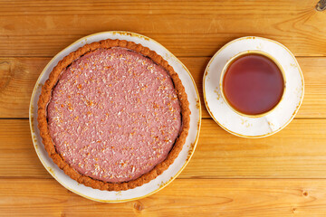 Homemade raspberry and banana pie and cup of tea on wooden table. Top view.