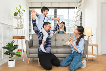Happy dad lifting excited daughter girl playing airplane with flying open hand in living room.Asian...