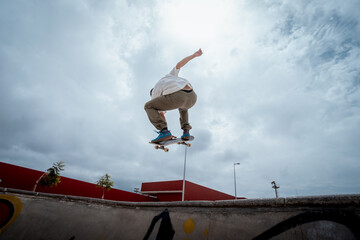 young skateboarder jumps over a bowl in a skate park