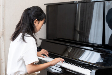 アップライトピアノを弾く日本人の女の子
