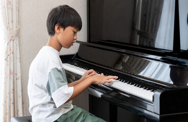 アップライトピアノを弾く日本人の男の子