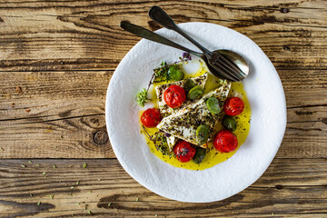 Roasted tomatoes with feta cheese and broad bean served  on wooden table