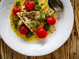 Roasted tomatoes with feta cheese and broad bean served  on wooden table