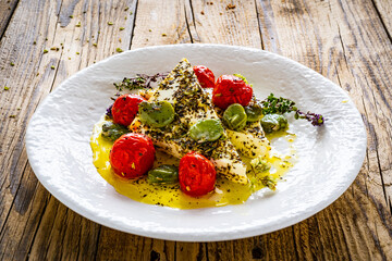 Roasted tomatoes with feta cheese and broad bean served  on wooden table