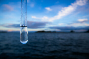 Water sample. Test tube with water. Sea and blue sky in the background. Water purity analysis and...